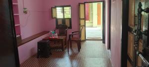Un pasillo con una mesa y una silla en una habitación rosa. en Ashwin Home Stay Room, en Tiruvannāmalai