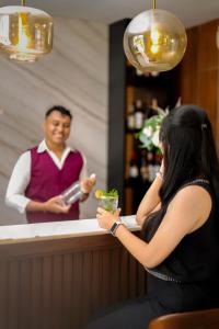 a woman standing at a bar with a drink at Mahameru Uluwatu in Uluwatu +66 photos