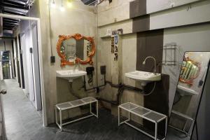 a bathroom with two sinks and a mirror on the wall at Hash Capsule Hostel Silom Soi 3 in Bangkok