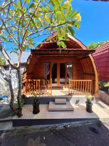 a small wooden house with a tree in front of it at Kubu Telaga Guest House in Uluwatu