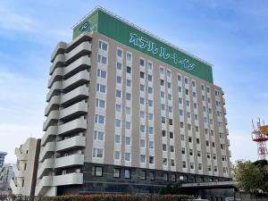 een gebouw met een groen bord erop bij Hotel Route-Inn Yatsushiro in Yatsushiro