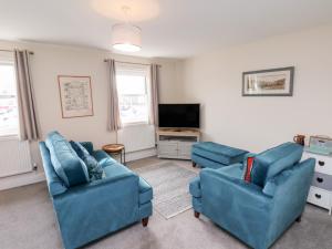 a living room with two blue chairs and a tv at Rails End in Whitby