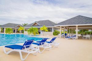 a group of blue and white chairs next to a swimming pool at Tropical 3 Bedroom Villa - Ocho Rios in Priory