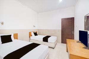 ボゴールにあるHotel O Bogor near Taman Safari formerly Hotel Rudian 2のベッド2台とテレビのある寝室 +19枚の写真