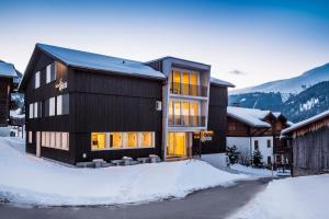 a black building with snow in front of it at Nova Casa Spinatscha Sedrun in Sedrun