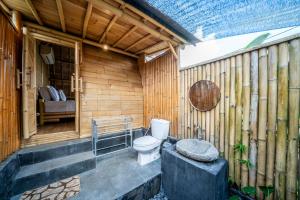 a bathroom with a toilet in a wooden wall at Tegal Bamboo Cottages & Private Hot Spring in Baturaja +66 photos