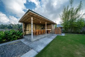 a small house with a wooden roof with a yard at Tegal Bamboo Cottages & Private Hot Spring in Baturaja