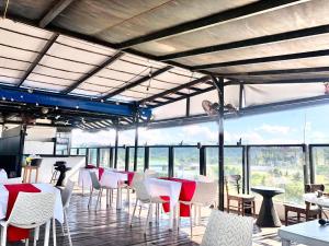 un restaurant avec des tables et des chaises blanches et des fenêtres dans l'établissement UpperHouse Hotel Formerly Pacifico Boutique by Hiverooms, à Cagayán de Oro
