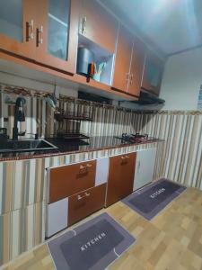 a kitchen with counters and cabinets and mats on the floor at Homestay Gaharu Syariah Dieng in Dieng