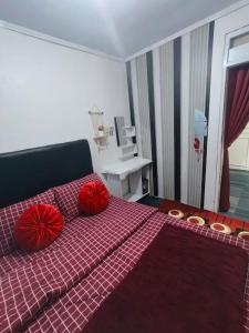 a bedroom with a red bed with red pillows on it at Homestay Gaharu Syariah Dieng in Dieng