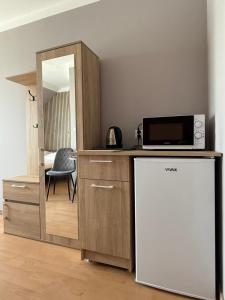 a kitchen with a refrigerator and a microwave and a mirror at Pensjonat Wiktoria in Międzywodzie