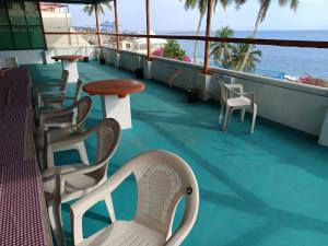 a balcony with chairs and tables and the ocean at Hotel Thiruvathira in Trivandrum