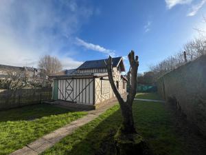 ein kleines Gebäude in einem Hof mit einem Baum in der Unterkunft Maison au calme au pied du parc Saint Pierre, proche cathédrale, hortillonnages et gare in Amiens
