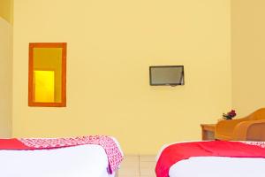 a room with two beds and a tv on the wall at Hotel O Bandar Lampung Near Teropong Kota Bukit Cindy Formerly Divka Residence in Tanjungkarang +22 photos