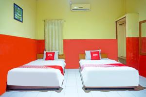 two beds in a room with red and yellow walls at Hotel O Bandar Lampung Near Teropong Kota Bukit Cindy Formerly Divka Residence in Tanjungkarang