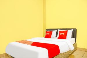 a bedroom with a bed with two red pillows at Hotel O Bandar Lampung Near Teropong Kota Bukit Cindy Formerly Divka Residence in Tanjungkarang