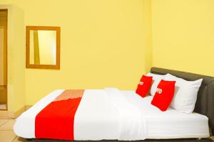 a bedroom with a bed with red and white pillows at Hotel O Bandar Lampung Near Teropong Kota Bukit Cindy Formerly Divka Residence in Tanjungkarang