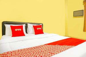 a bed with two red pillows on top of it at Hotel O Bandar Lampung Near Teropong Kota Bukit Cindy Formerly Divka Residence in Tanjungkarang