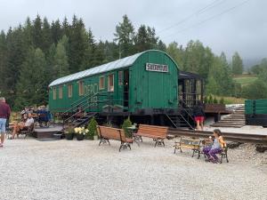 a green train car sitting on the tracks with people at Drevenica U Feleja in Pohorelá +8 photos
