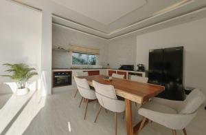 a kitchen with a wooden table and white chairs at Happy Palms - Jungle View Villa in Mae Nam