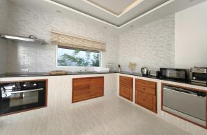 a large kitchen with wooden cabinets and a window at Happy Palms - Jungle View Villa in Mae Nam