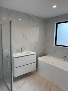 a bathroom with a white tub and a sink and a shower at New Luxury House in Christchurch in Christchurch +3 photos