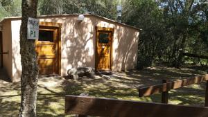 a small cabin with wooden doors in the woods at Camping U STABIACCIU in Porto-Vecchio