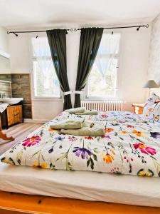 a bedroom with a large bed with a floral bedspread at Pension im Tal der Stille - Thale OT Treseburg in Thale