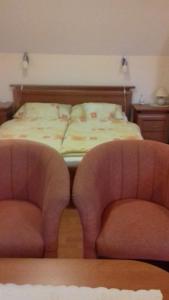 ein Schlafzimmer mit einem Bett mit zwei Stühlen davor in der Unterkunft Andor apartman in Hévíz
