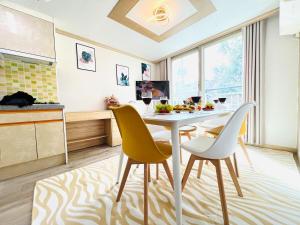 a kitchen with a white table and yellow chairs at Gamseong house next to Sung Sim Dang in Daejeon