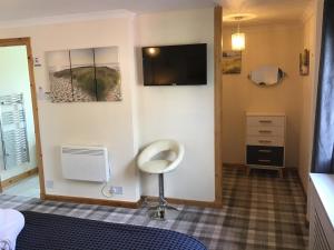 a room with a tv and a chair on a wall at Old School B&B Super King Exclusive 5 Room private suite in Orkney