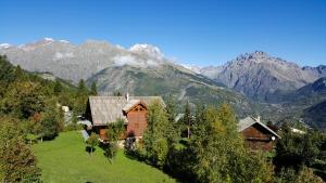 uma casa num campo com montanhas ao fundo em Les Ribambelles em Puy-Saint-Vincent