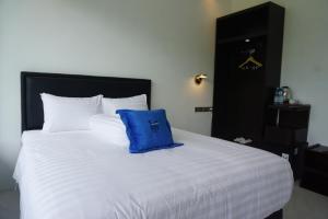 a large white bed with a blue pillow on it at Nyawang Lintang Villa in Pulau Kukup
