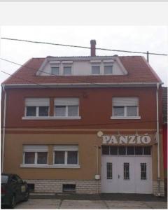ein rotes Gebäude mit einem Panikschild drauf. in der Unterkunft Napsugár Panzió in Vác