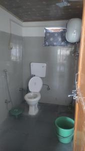 a bathroom with a toilet and a green bucket at Donmay homestay & guesthouse in Silapi
