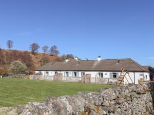a large white house with a stone wall at Larch in Newtonmore