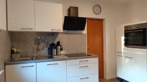 a kitchen with white cabinets and a sink and a clock at FeWo Marjenza in Wermelskirchen