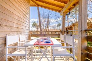 - une table et des chaises sur la terrasse couverte d'une cabine dans l'établissement Les Cottages du Lac A05, à Parentis-en-Born