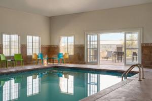 a swimming pool with colorful chairs and a table at La Quinta by Wyndham Shawnee in Shawnee
