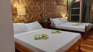two beds in a room with white sheets at Venida Farm in Sampong