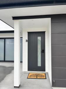 una porta d'ingresso nera con uno zerbino con stampa leopardata di Brand new Lakeside cozy room kaka a Taupo