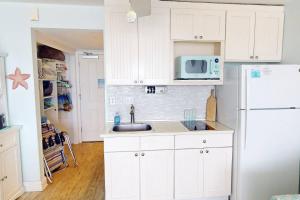 a kitchen with white cabinets and a white refrigerator at 318 - Island Inn in St. Pete Beach