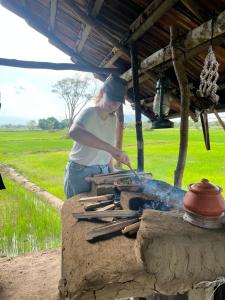 una mujer cocinando comida en la parte superior de una parrilla en Bissa Villa, en Habarana