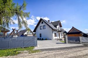 a white house with a fence in front of it at Domek Na Brzysku Lipnica Wielka in Lipnica Wielka