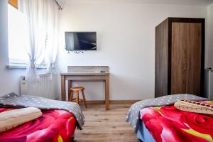 two beds in a room with a desk and a television at Domek Na Brzysku Lipnica Wielka in Lipnica Wielka