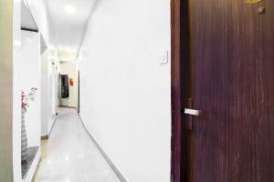 a hallway with a wooden door and a hallway with white walls at Collection O Karaya Road Formerly Hotel New Diamond in Kolkata