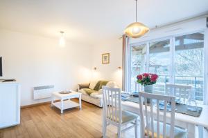 Appartement aux Cottages du Lac H70 في بارينتس إن بورن: غرفة معيشة مع طاولة وكراسي وأريكة