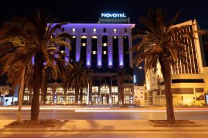 un bâtiment avec des palmiers en face d'une rue dans l'établissement Novotel Tunis, à Tunis
