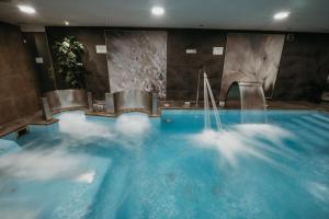 a large swimming pool with blue water in a building at AZZ Asturias LangreHotel & Spa in Langreo