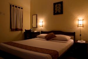 a bedroom with a bed with two lights on the wall at Andrea Hotel in Yogyakarta